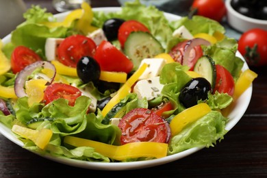 Photo of Delicious fresh Greek salad on wooden table, closeup