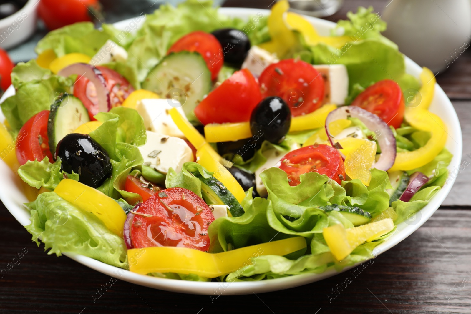 Photo of Delicious fresh Greek salad on wooden table, closeup