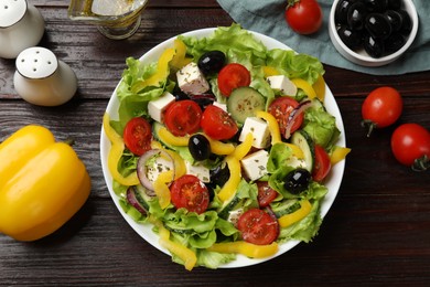 Photo of Delicious fresh Greek salad and ingredients on wooden table, flat lay