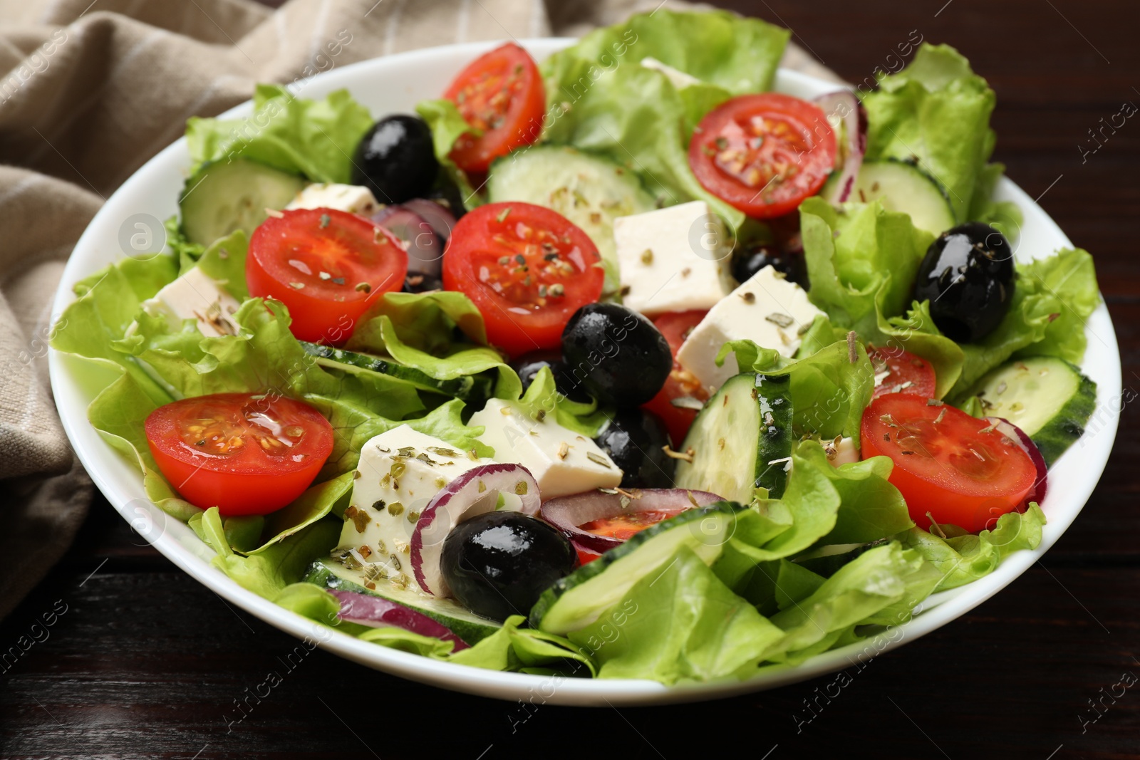 Photo of Delicious fresh Greek salad on wooden table, closeup