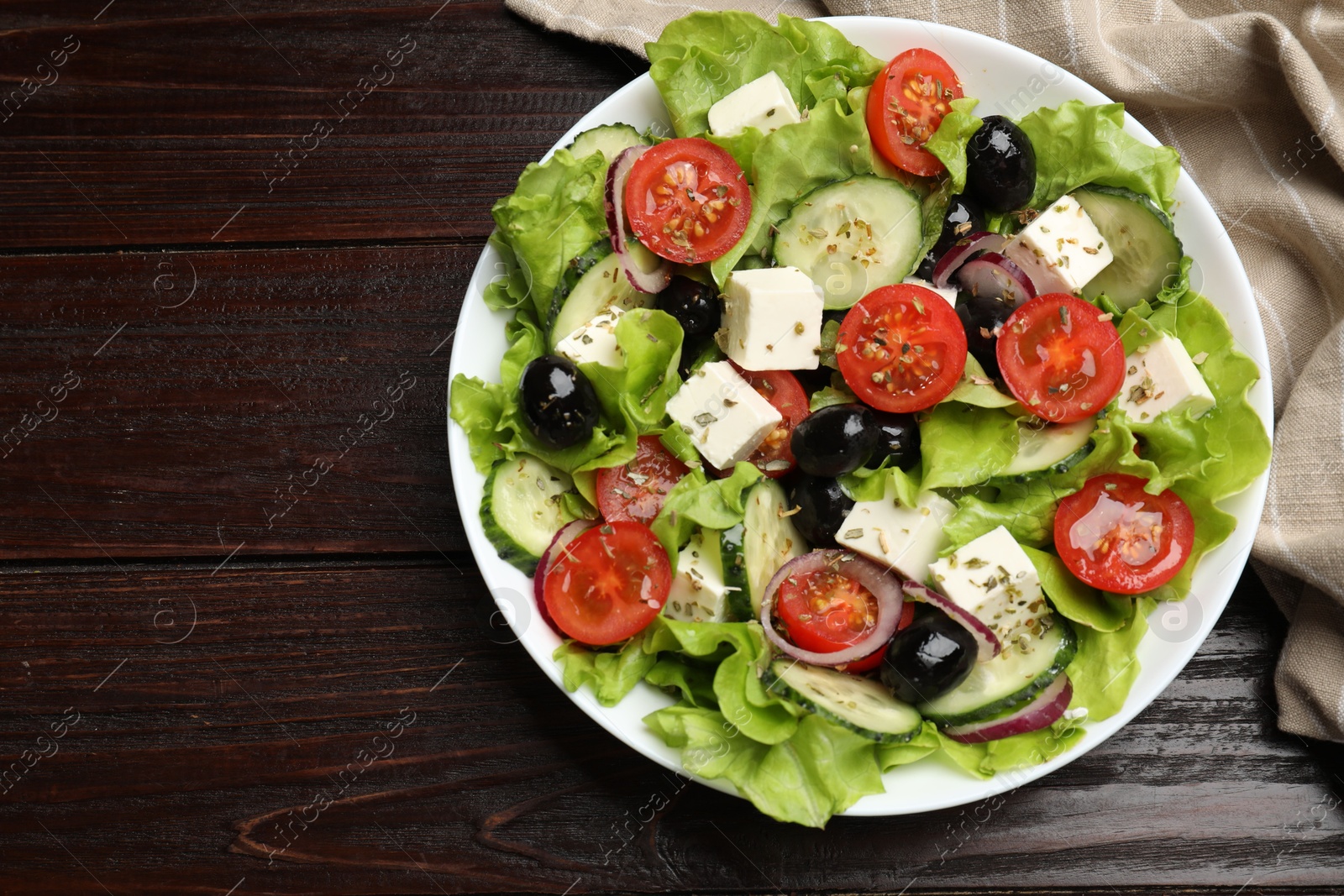 Photo of Delicious fresh Greek salad on wooden table, top view. Space for text