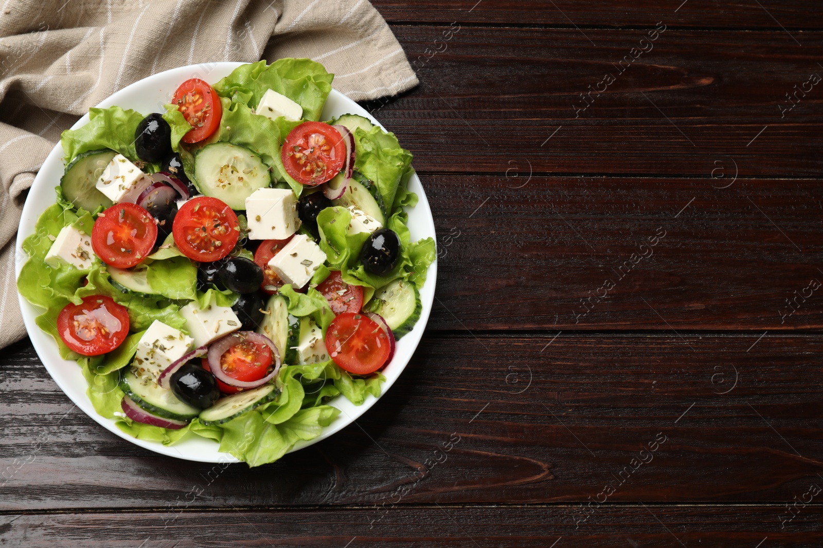 Photo of Delicious fresh Greek salad on wooden table, top view. Space for text