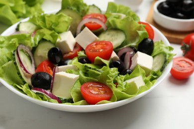 Photo of Delicious fresh Greek salad on white table, closeup