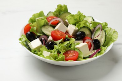 Photo of Delicious fresh Greek salad on white table, closeup