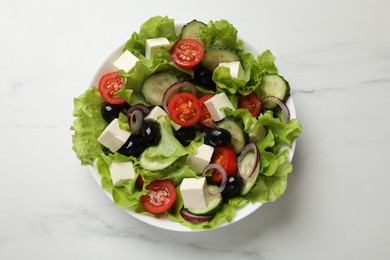 Photo of Delicious fresh Greek salad on white marble table, top view