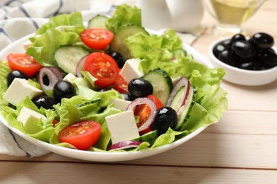 Photo of Delicious fresh Greek salad on light wooden table, closeup