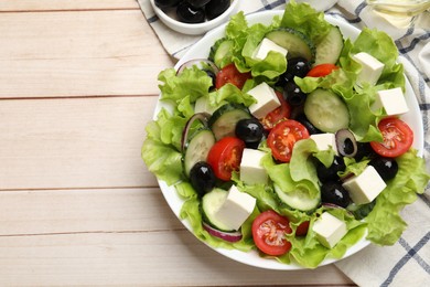 Photo of Delicious fresh Greek salad on light wooden table, flat lay. Space for text