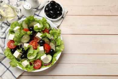 Photo of Delicious fresh Greek salad and ingredients on light wooden table, flat lay. Space for text