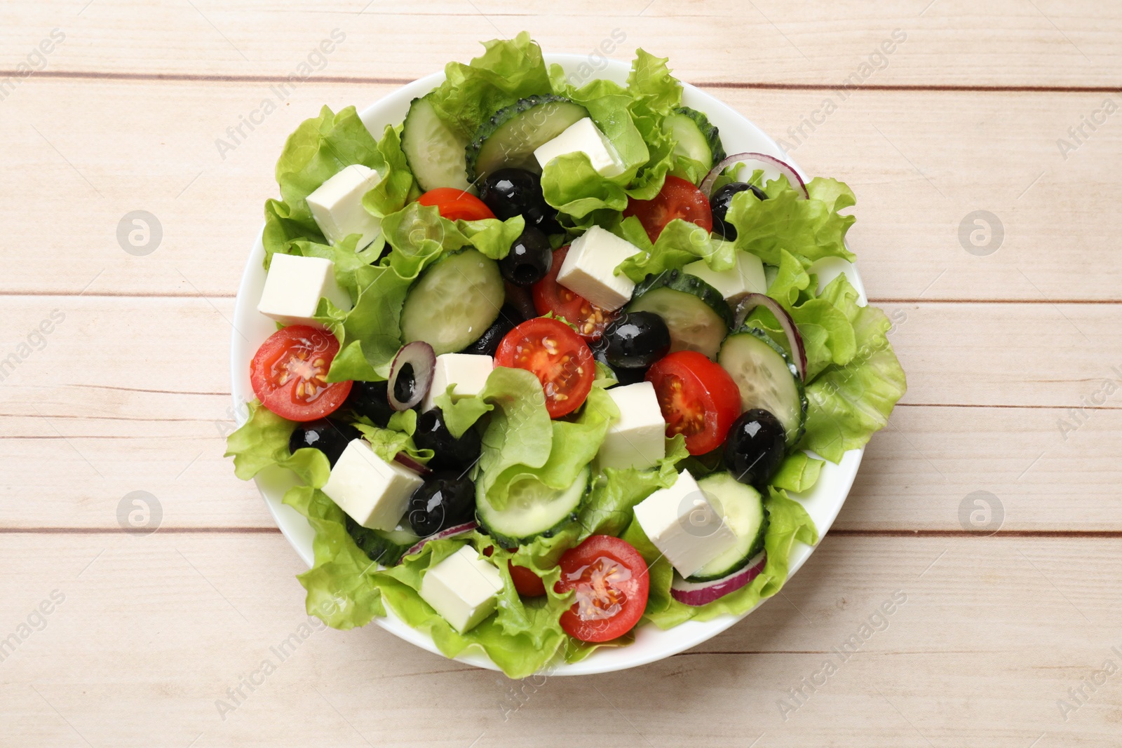 Photo of Delicious fresh Greek salad on light wooden table, top view