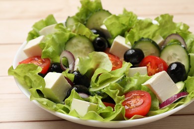 Photo of Delicious fresh Greek salad on light wooden table, closeup