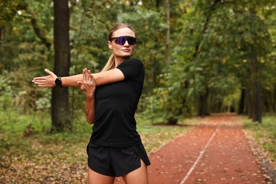 Photo of Young athletic woman stretching in park, space for text