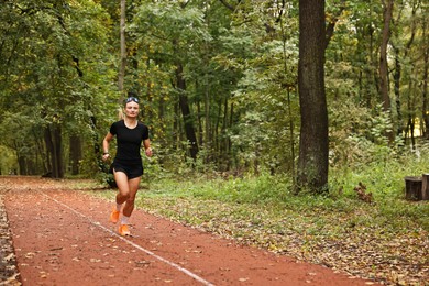 Photo of Athletic woman running in park, space for text