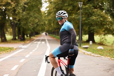 Photo of Athletic man with helmet riding bicycle outdoors, space for text