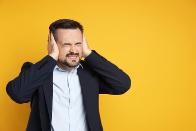 Photo of Man covering his ears on orange background, space for text