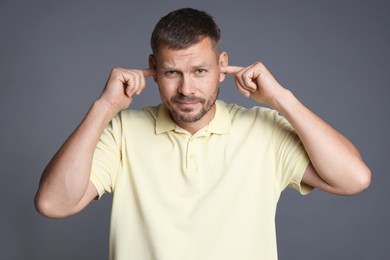 Photo of Man covering his ears with fingers on grey background