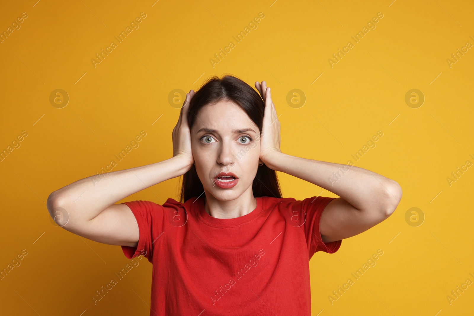 Photo of Woman covering her ears on orange background