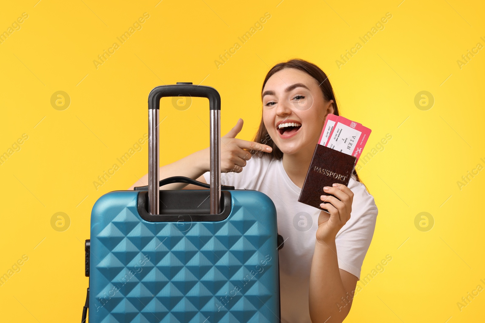 Photo of Woman with tickets, passport and suitcase on orange background