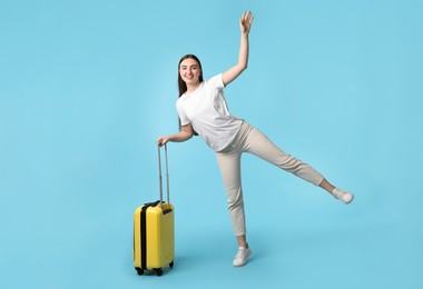 Photo of Woman with vintage camera and suitcase on light blue background