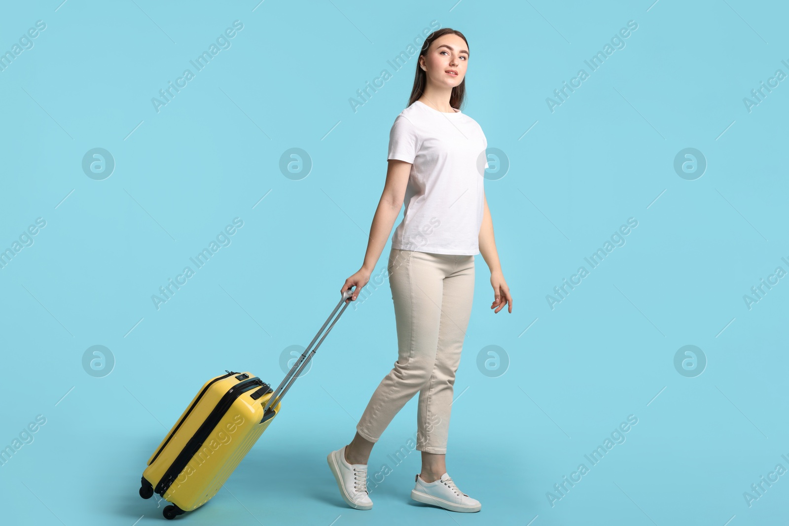 Photo of Woman with suitcase on light blue background