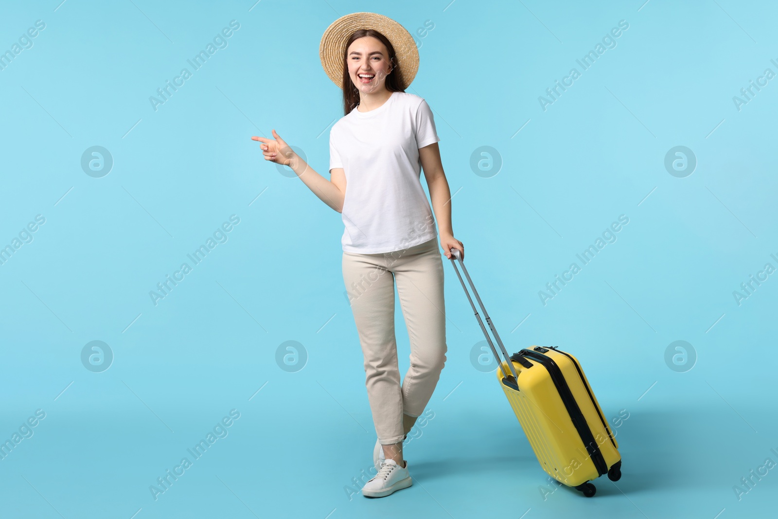 Photo of Woman in straw hat with suitcase on light blue background