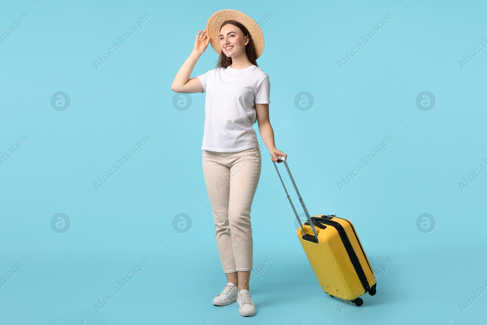 Photo of Woman in straw hat with suitcase on light blue background