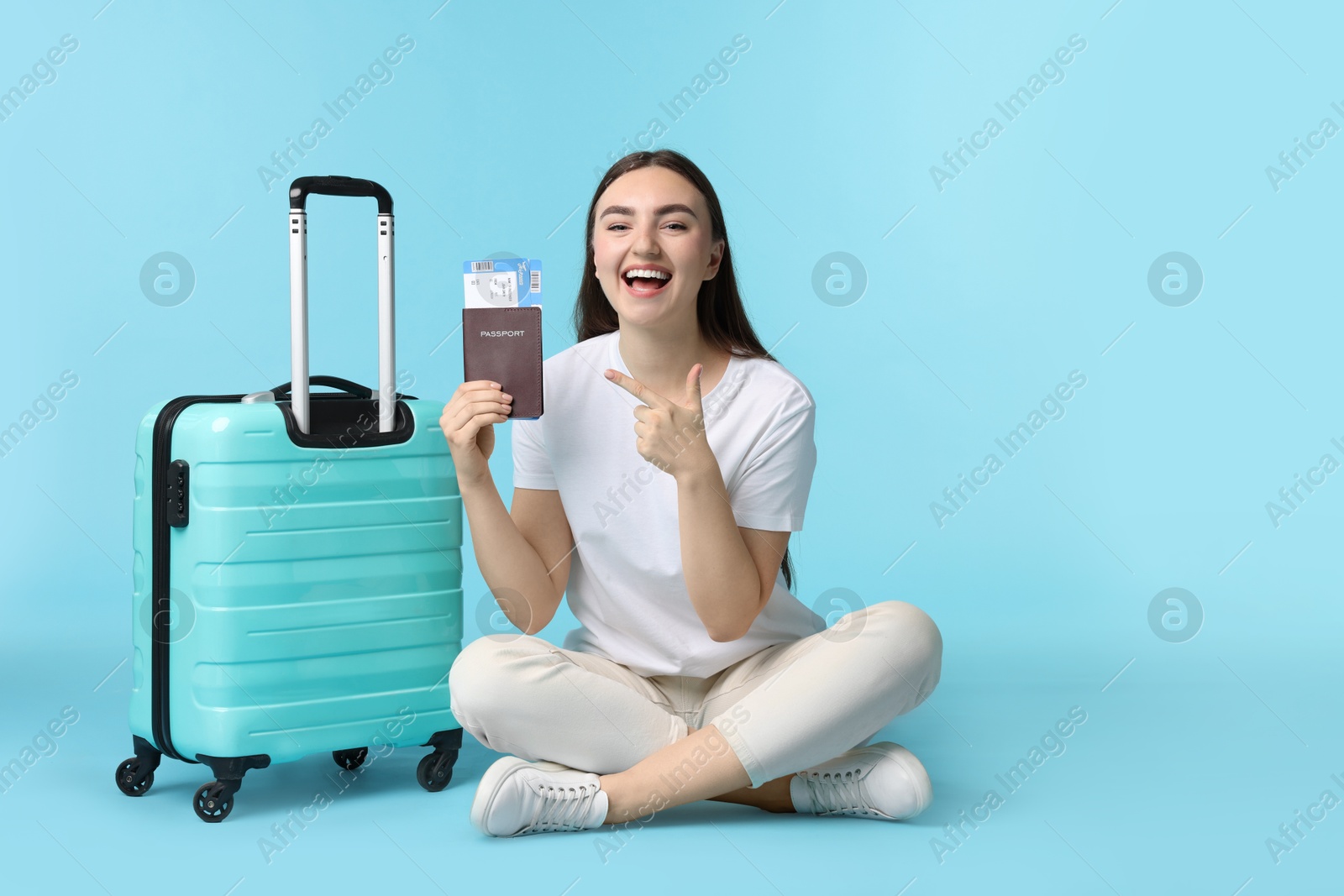 Photo of Woman with ticket, passport, and suitcase on light blue background