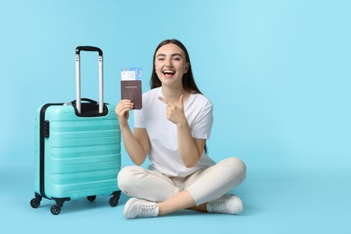 Photo of Woman with ticket, passport, and suitcase on light blue background