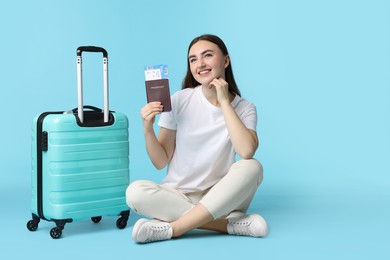 Woman with ticket, passport, and suitcase on light blue background