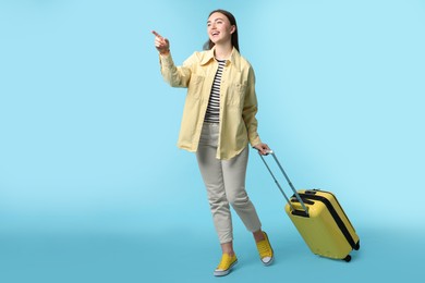 Woman with suitcase on light blue background