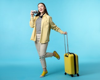 Photo of Woman with vintage camera and suitcase on light blue background