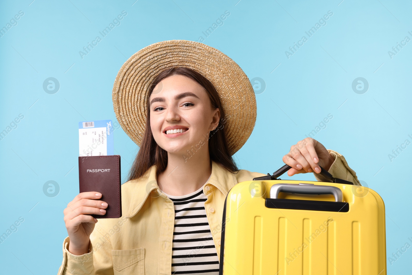 Photo of Woman with ticket, passport and suitcase on light blue background