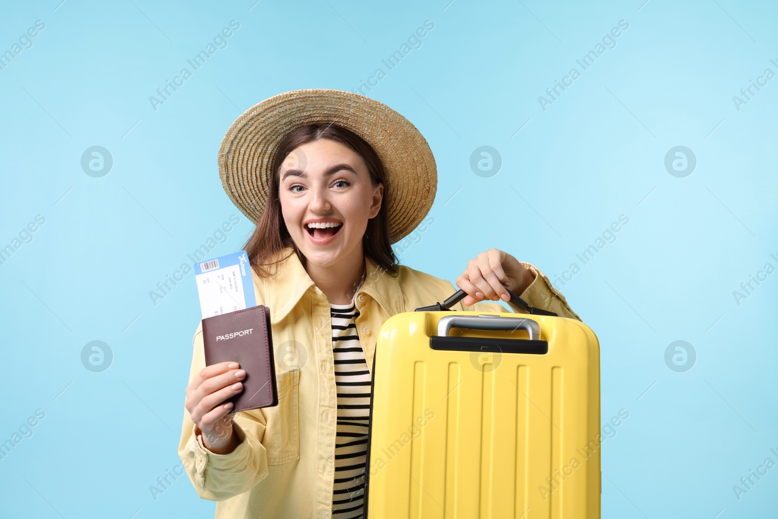 Photo of Woman with ticket, passport and suitcase on light blue background