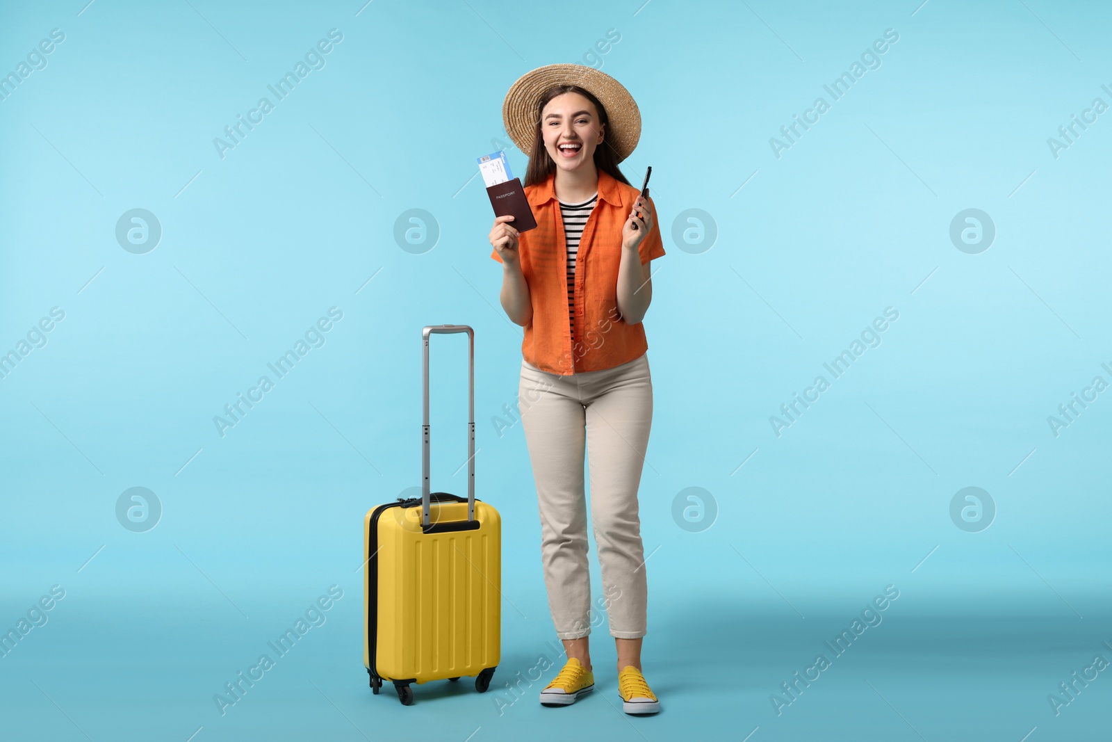 Photo of Woman with ticket, passport, suitcase and smartphone on light blue background