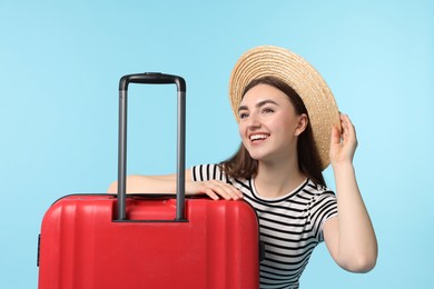 Photo of Woman in straw hat with suitcase on light blue background