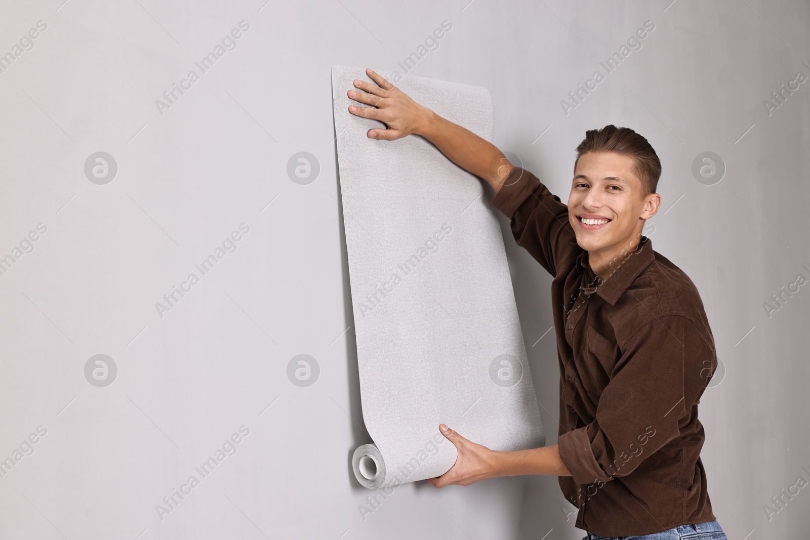 Photo of Smiling handyman hanging wallpaper indoors. Space for text