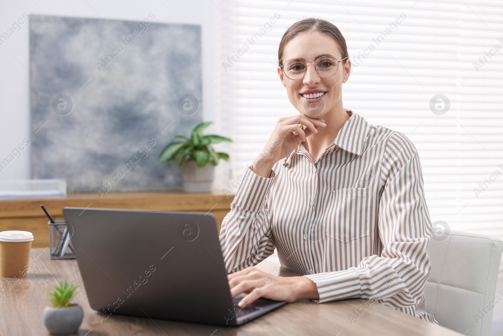 Photo of Programmer working on laptop at wooden desk indoors