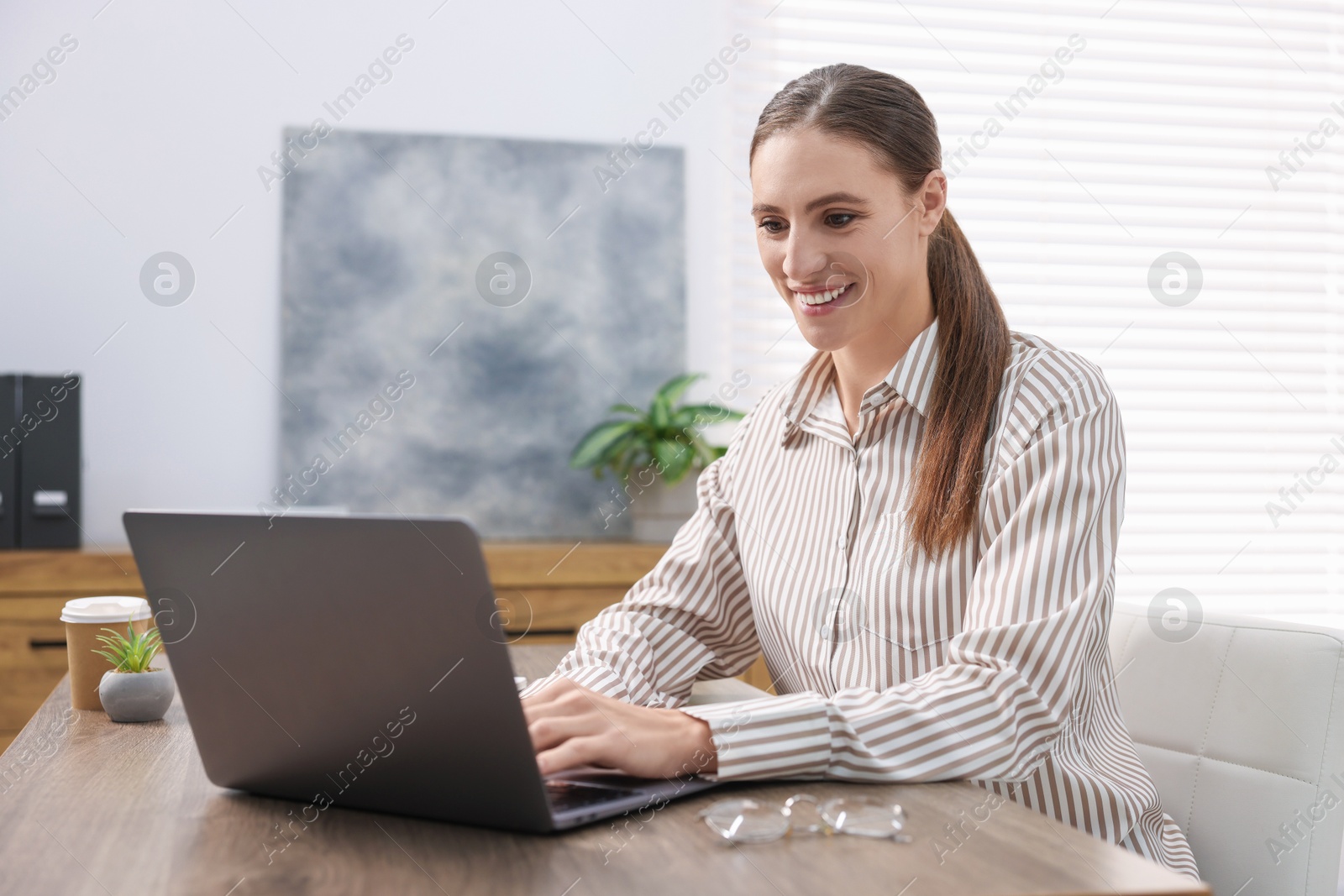 Photo of Programmer working on laptop at wooden desk indoors