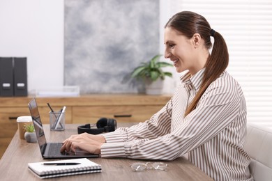 Photo of Programmer working on laptop at wooden desk indoors