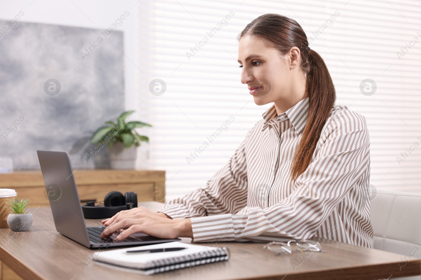 Photo of Programmer working on laptop at wooden desk indoors