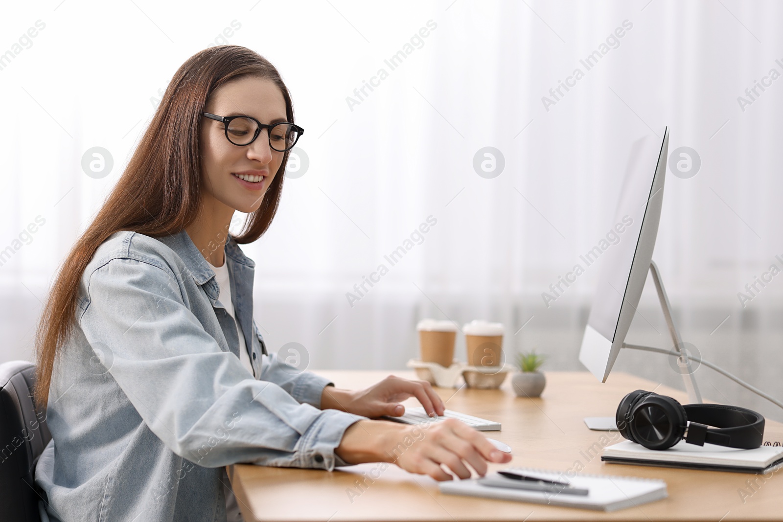 Photo of Programmer working on computer at wooden desk indoors