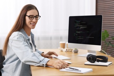 Photo of Programmer working on computer at wooden desk indoors