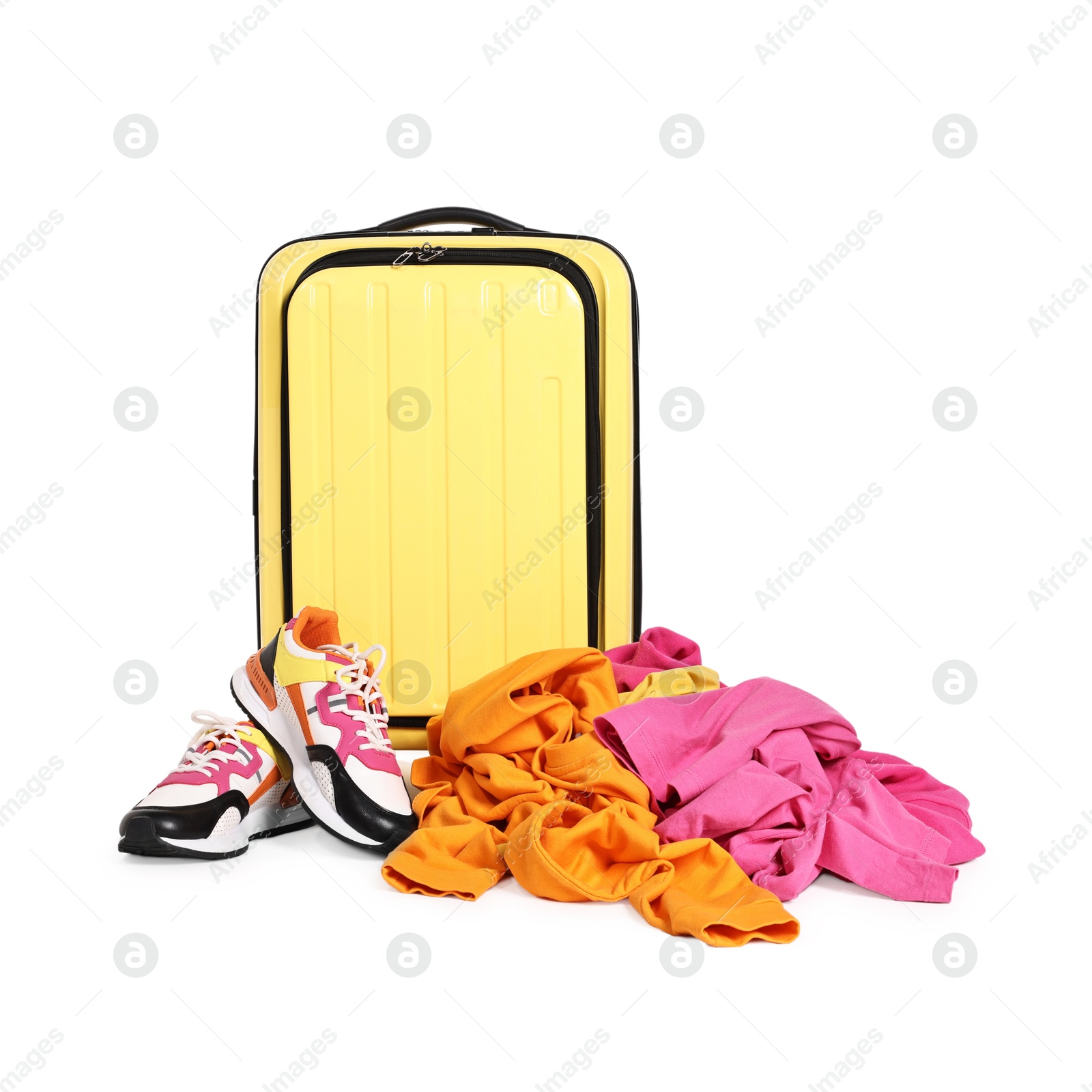 Photo of Yellow suitcase, pile of different messy clothes and sneakers isolated on white