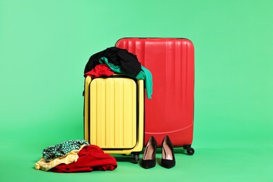 Photo of Suitcases, messy clothes and shoes on green background