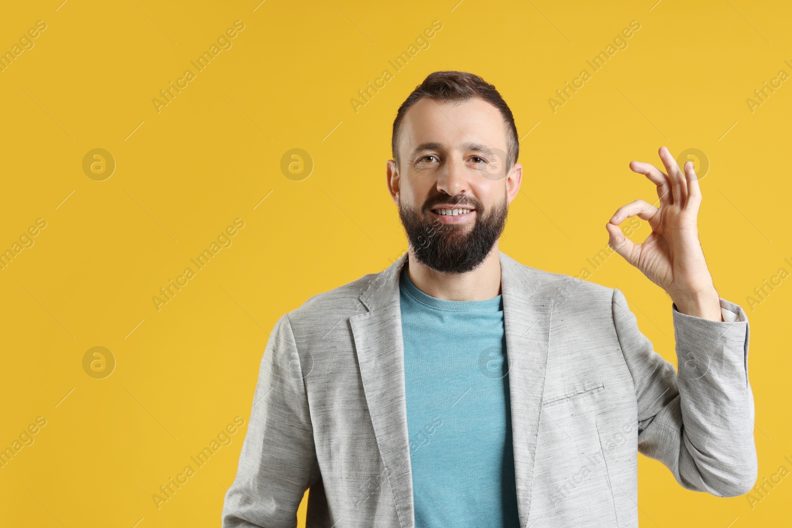 Photo of Man showing okay gesture on orange background. Space for text