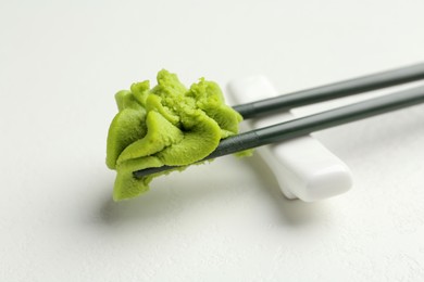 Photo of Chopsticks with hot wasabi paste on light textured table, closeup