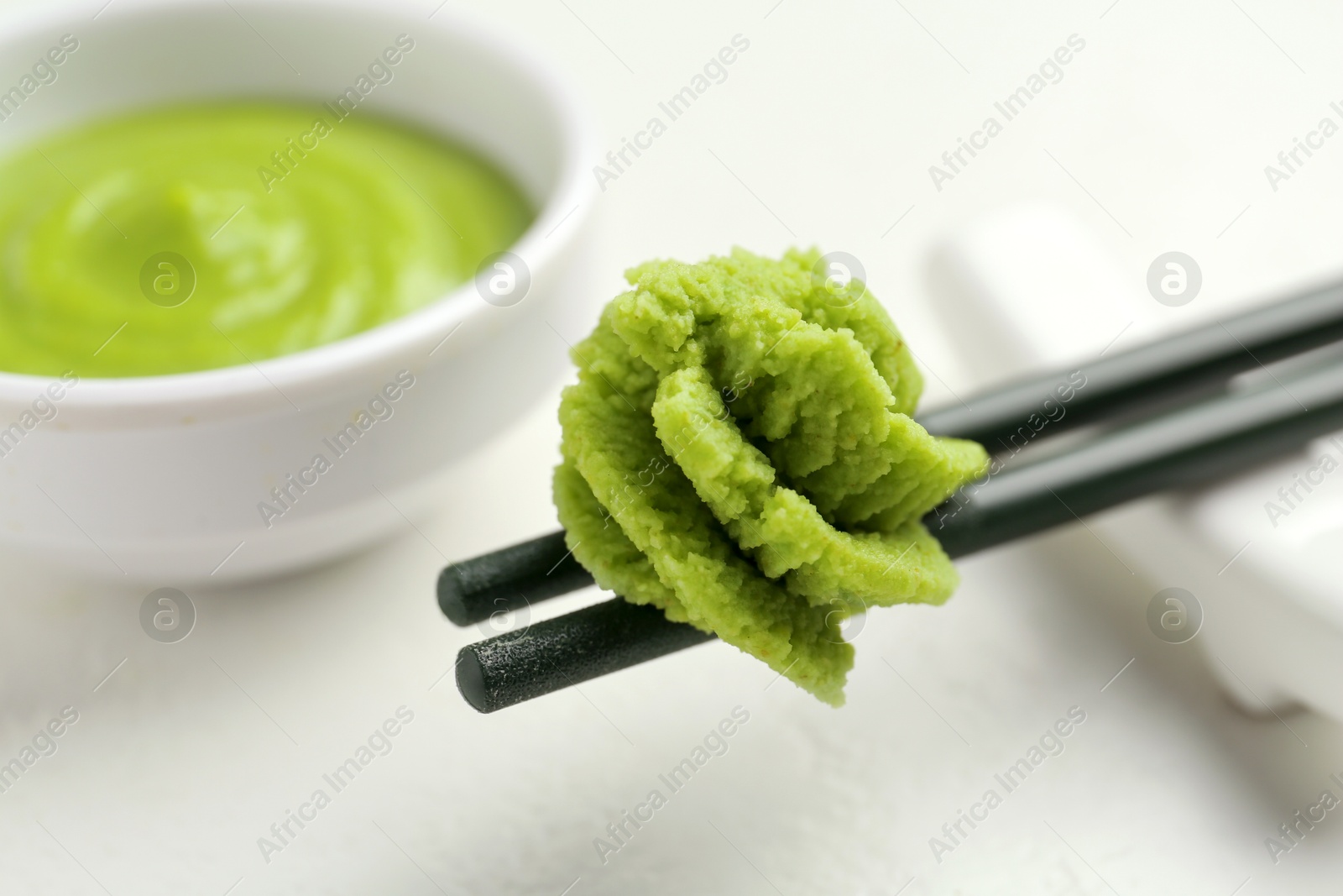 Photo of Chopsticks with hot wasabi paste on light table, closeup