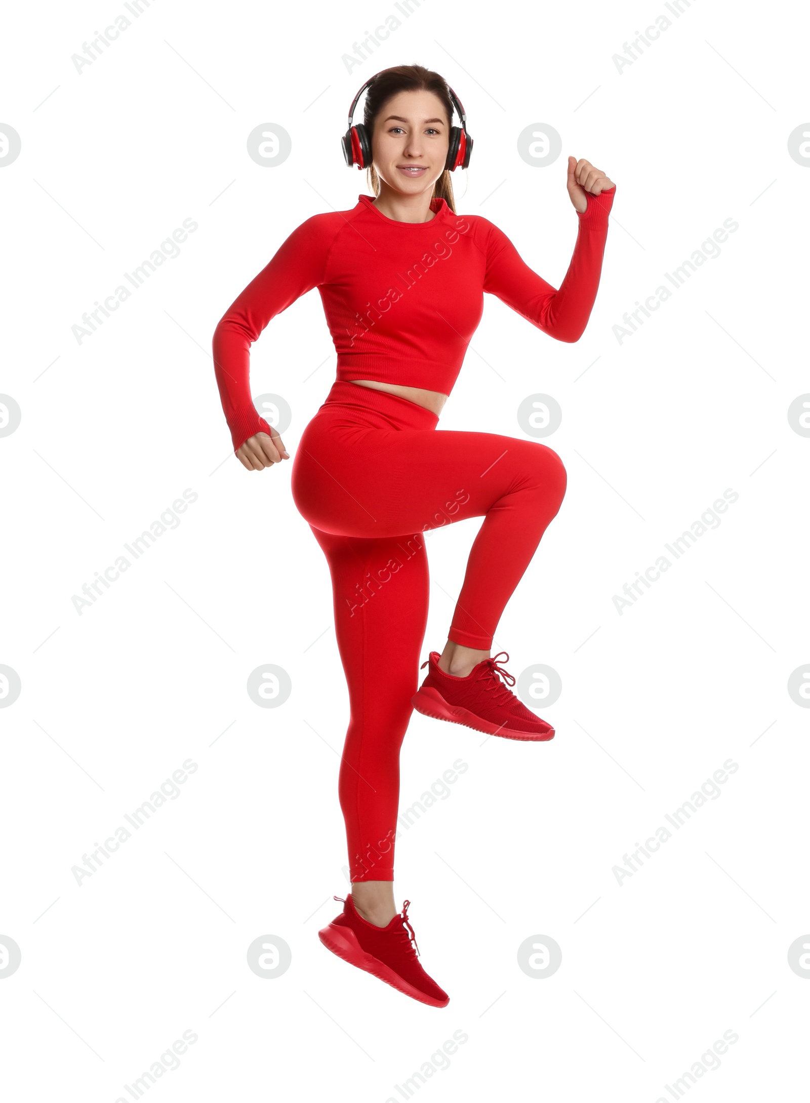 Photo of Woman in sportswear and headphones exercising on white background