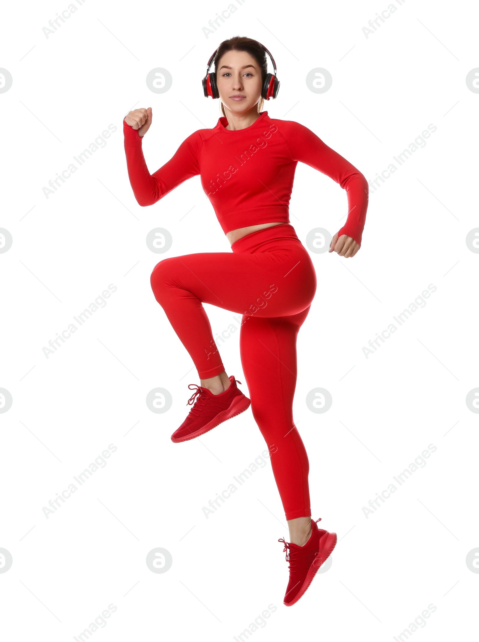 Photo of Woman in sportswear and headphones exercising on white background