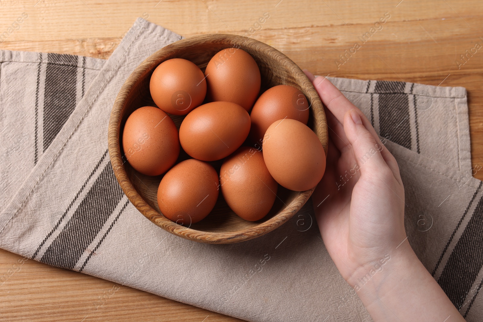 Photo of Woman with raw eggs at wooden table, top view