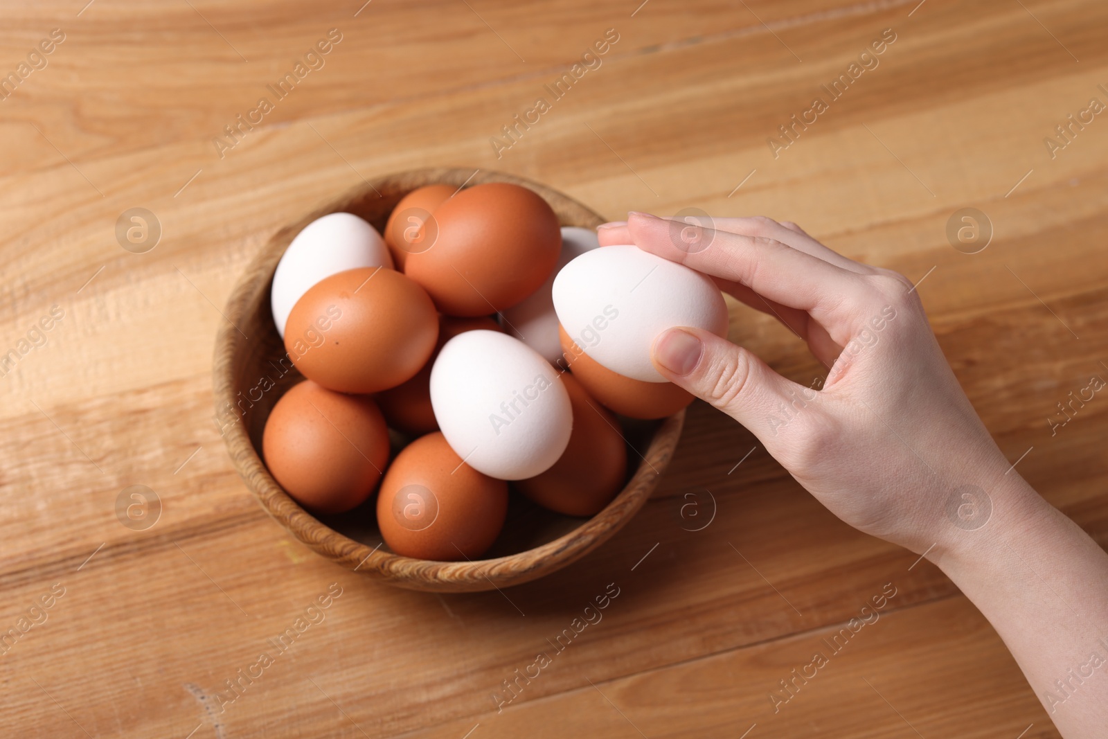 Photo of Woman with raw eggs at wooden table, closeup